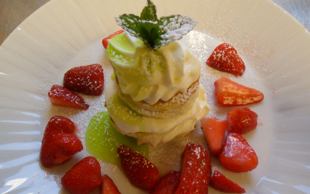Pastry with custard, cut strawberries and a green sauce