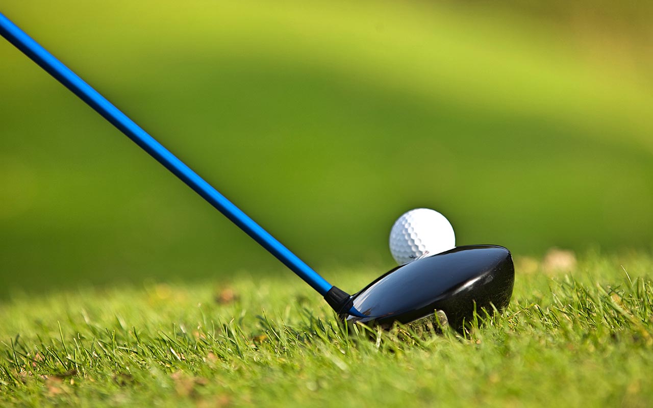 Detail eines Golfschlägers der einen Ball berührt