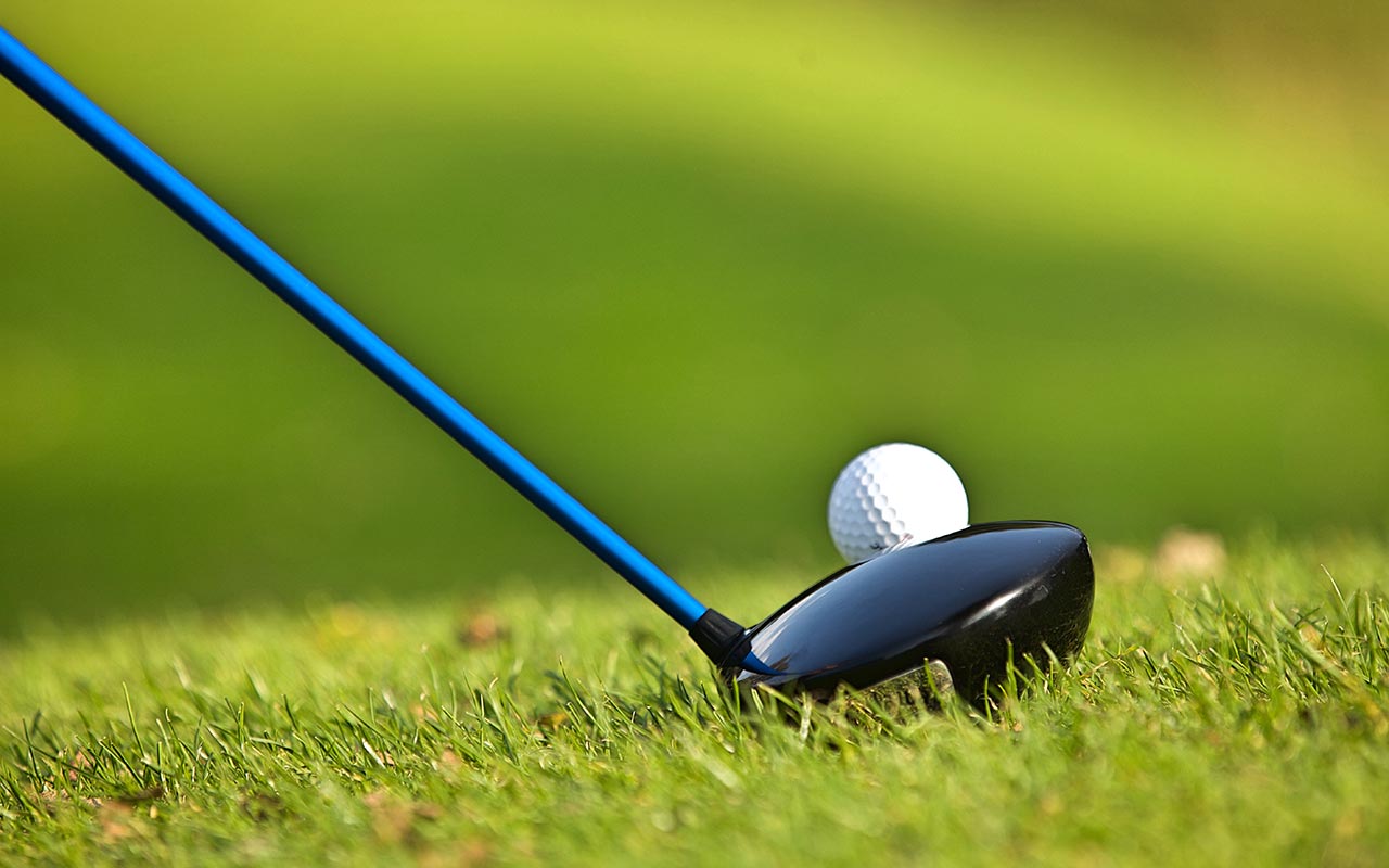 Detail of a golf club touching a little ball