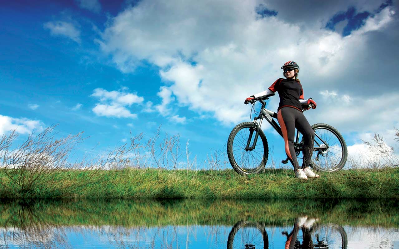 Frau an ein Mountainbike gelehnt am Flussufer