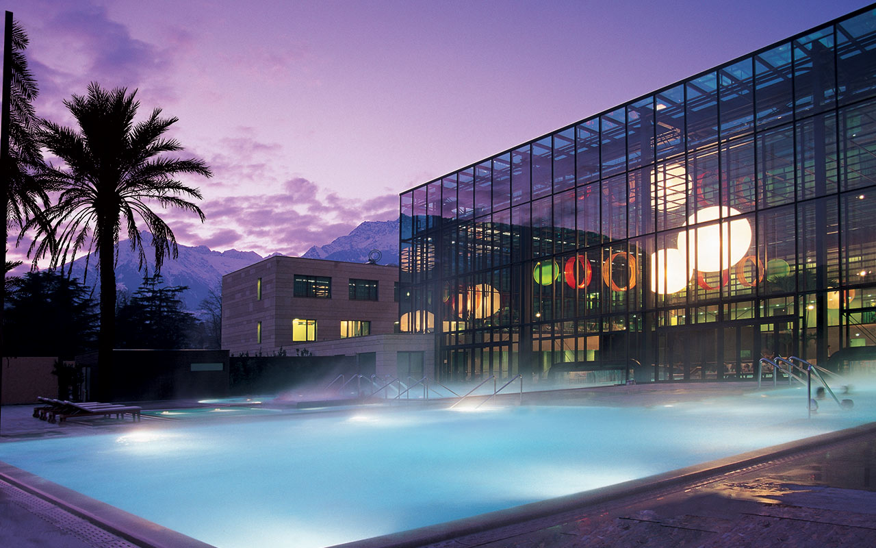 Piscina con acqua calda all'aperto e le Terme di Merano sullo sfondo