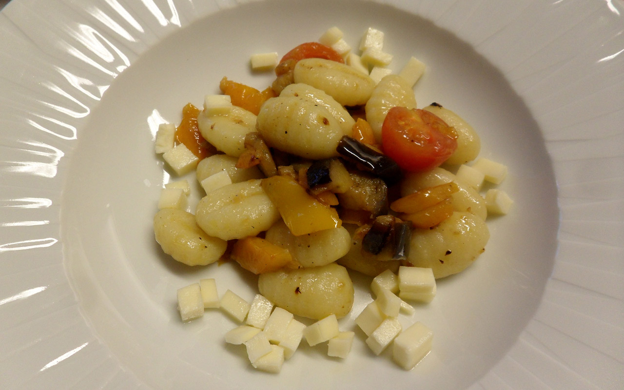 Gnocchi con formaggio e verdure in un piatto bianco