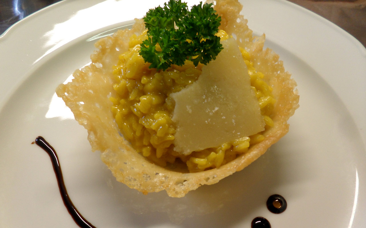 Risotto served in a parmesan container with parsley leaves